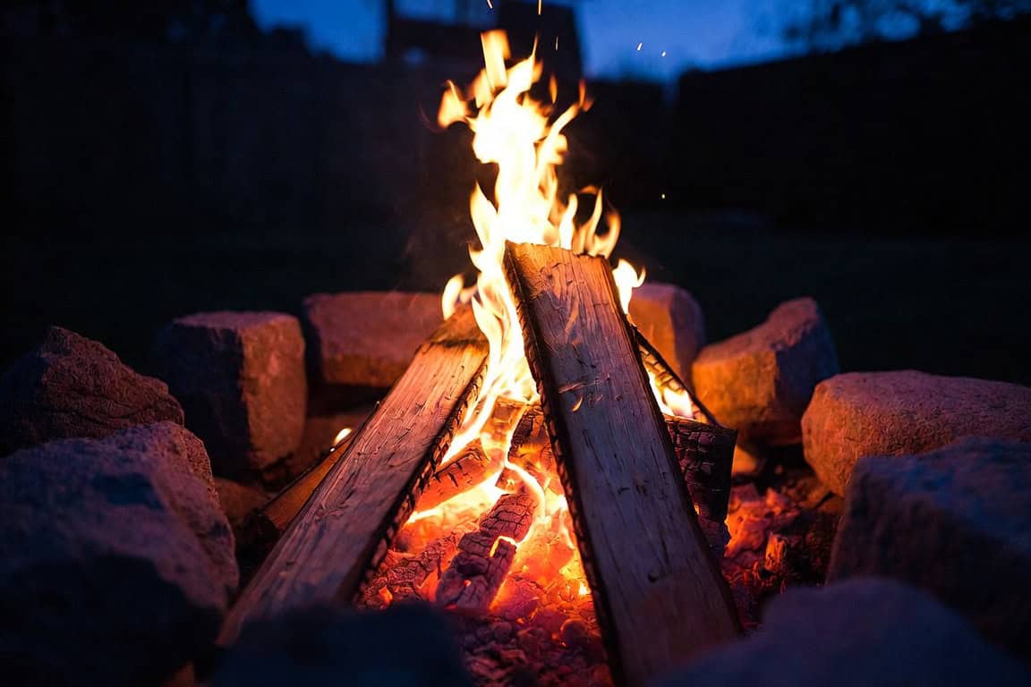 A fire built on purpose: stacked logs burning over a deep bed of coals